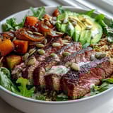 Sliced steak and creamy avocado top vibrant greens in a hearty bowl.