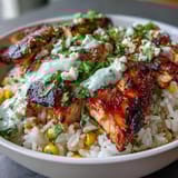 Sliced grilled chicken, cotija cheese, and fresh cilantro garnish these Street Corn Chicken and Rice Bowls served with lime wedges.