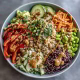 Creamy coconut-infused quinoa topped with crisp red bell peppers, shredded carrots, and purple cabbage for a nourishing meal.  