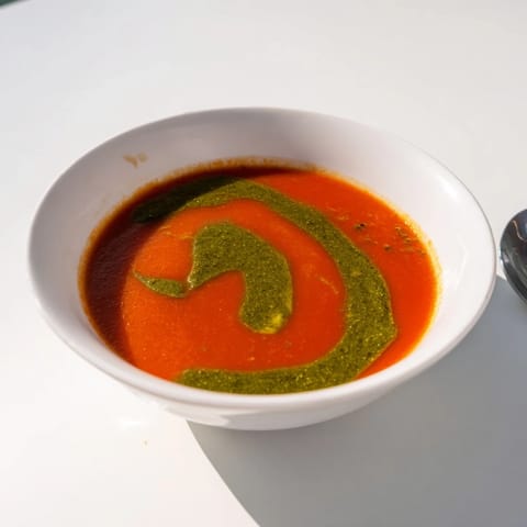 Creamy Tomato Soup with Basil Pesto Swirl served in a rustic bowl, with a vibrant green swirl on top.