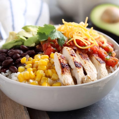 Layers of spicy chicken, black beans, and corn in this hearty Spicy Chicken Burrito Bowl with fresh avocado slices.