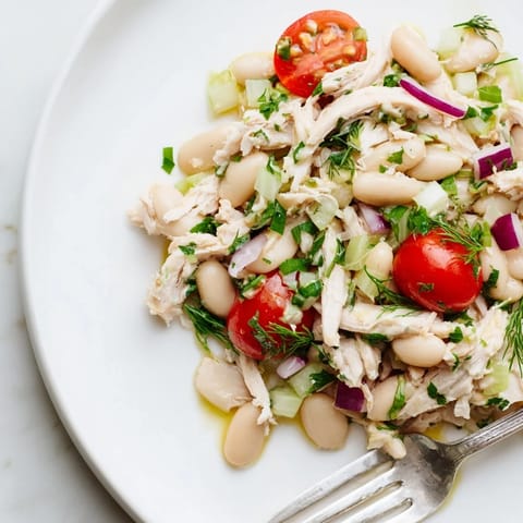 Bright Lemony White Bean Chicken Salad with juicy chicken, white beans, and herbs tossed in lemon vinaigrette, plated with a fork.