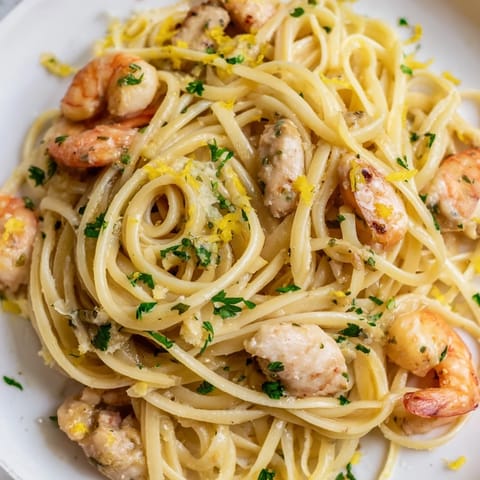 Freshly cooked Lemon Garlic Shrimp & Chicken Pasta steaming in a white bowl, showcasing tender chicken, succulent shrimp, and bright parsley over al dente spaghetti.  