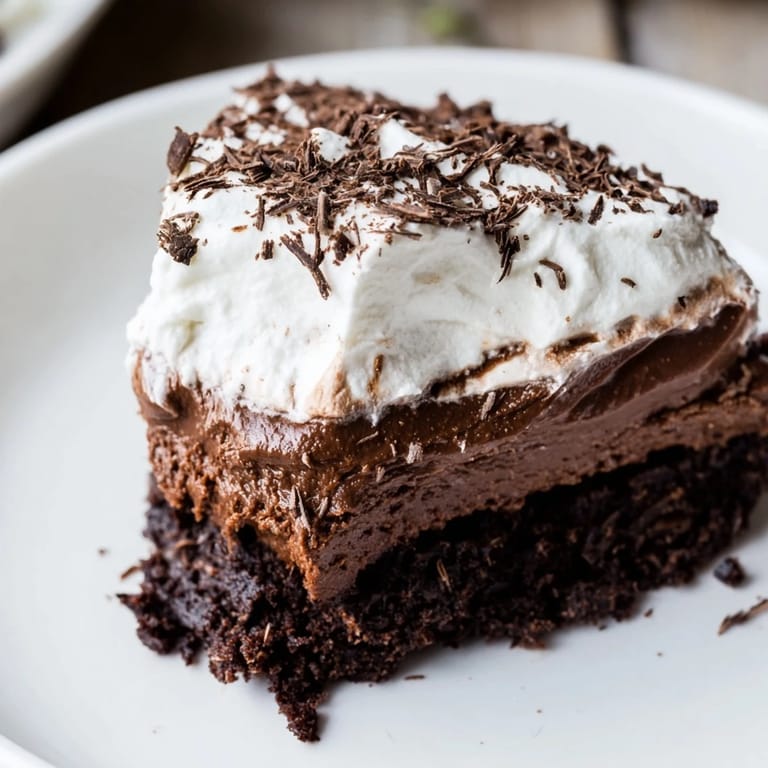 Creamy whipped topping adorns a decadent Mississippi Mud Pie with chocolate shavings, ready to serve.