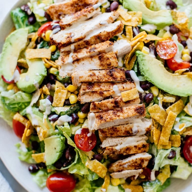 Overhead view of Crunchy Taco Chicken Salad, loaded with corn, tomatoes, cheese, and crushed taco shells for a Tex-Mex meal.