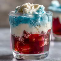 Vibrant red, white, and blue layered Jello cups with smooth stripes, ideal for festive summer parties or Fourth of July celebrations.